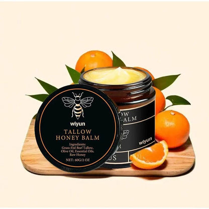 Nomilora Beef Tallow Honey Balm in a jar with oranges on a wooden board.